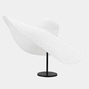 Detail of white oversized wide brim straw hat featuring elegant woven texture and wavy design