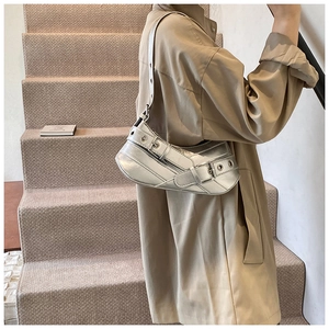 Silver metallic underarm bag with decorative buckles and metal eyelets worn by a model