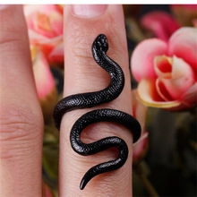 Vista macro de un anillo de serpiente negra con detalles de resina en el dedo