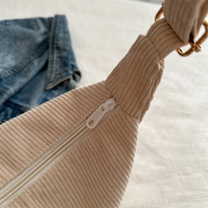 Cream corduroy tote bag featuring a secure zipper closure and gold-toned metal hardware