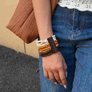 Detail of bohemian multilayer wood bead bracelet with orange and brown geometric accents