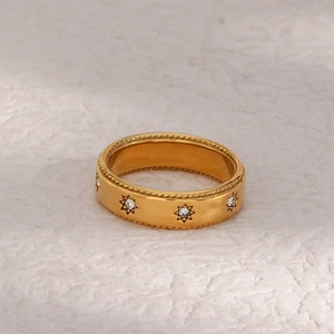 Détail macro d'une bague dorée avec étoile en zircone et bordure à texture tressée