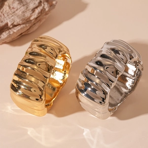 Irregular textured gold and silver wide bangles with wavy metal design shown at 45-degree angle