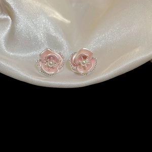 Detail of pink rose earrings with pearl center and crystals on silk fabric