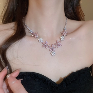 Gros plan d'un collier de fleurs élégant avec des zircons roses et clairs sur un modèle