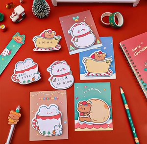 Flat lay of a Christmas stationery set featuring bear motifs and pencils on a red background