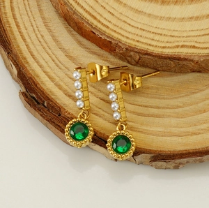 Detail of vintage emerald green crystal drop earrings with pearls on wood