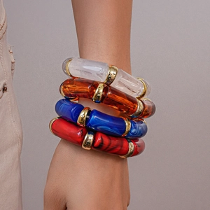 Detailed close-up of acrylic resin bangles showing marble textures and gold metal link joints