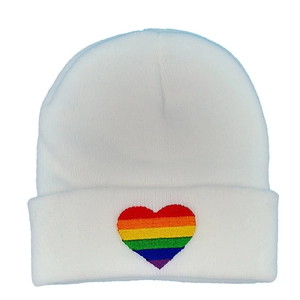 White knit beanie hat with rainbow heart embroidery in a professional flat lay view