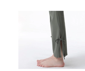 Detail of crossover yoga pants featuring side slit hem and decorative bow tie in olive green