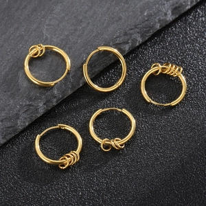 Set of five golden stainless steel hoop earrings with small charms on dark stone surface