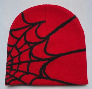 Close-up of red knitted beanie with black spider web jacquard pattern detail