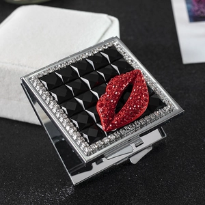 Close-up of square metal compact mirror with black checkered pattern and red crystal lips