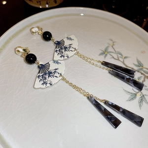 Détail de boucles d'oreilles en éventail avec motif bambou et glands en résine sur plat