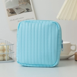 Close-up of light blue quilted leather pouch showing vertical stitching and zipper detail