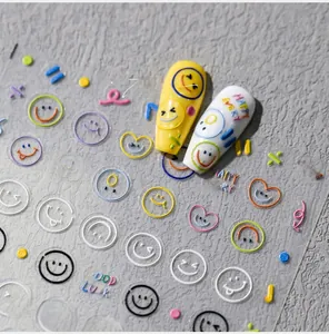 Dettagli di adesivi per unghie con smile colorati e cuori su manicure gialle e bianche