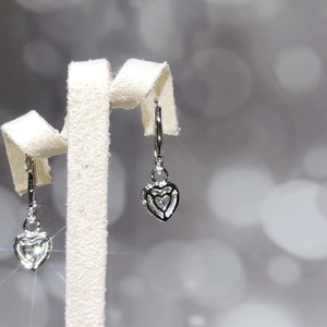 Macro detail of silver heart drop earrings with sparkling cubic zirconia on T-stand