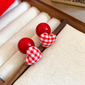Macro shot of red heart earrings with fabric texture and ball backing on jewelry tray