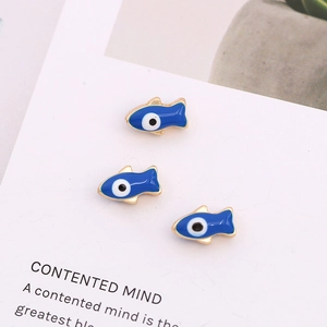 Three blue fish-shaped evil eye enamel charms with gold edges on white background