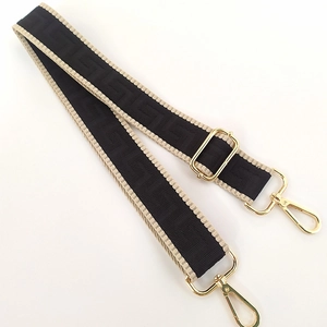 Detail of adjustable woven canvas strap with Greek key pattern and gold metal hooks