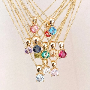 Detail view of gold-plated necklaces with various colorful gemstone pendants on fine chains