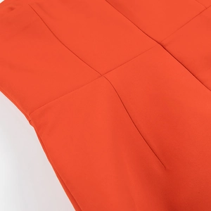 Dettaglio dell'abito a tubino rosso-arancio con cuciture precise e tessuto liscio