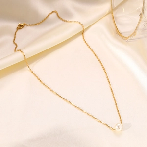 Close-up of minimalist pearl necklace with thin gold chain on cream silk fabric