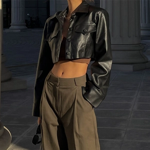 Détail d'une veste courte en cuir noir avec col à revers et boutons simples pour femmes