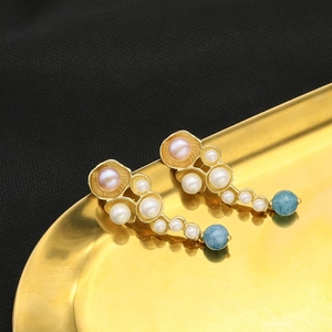 Elegant gold drop earrings with natural pearls and blue beads on a metallic tray