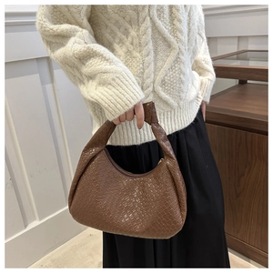 Detail of a dark brown woven leather handbag with a knotted handle and metallic zipper