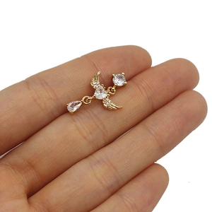 Close-up showing a heart-shaped zircon nose stud with wing design on a finger for scale
