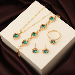 Detail view of a 4-piece jewelry set with green heart crystals on a white display box