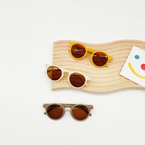 Three pairs of cute round-frame children's sunglasses in yellow, beige, and brown colors