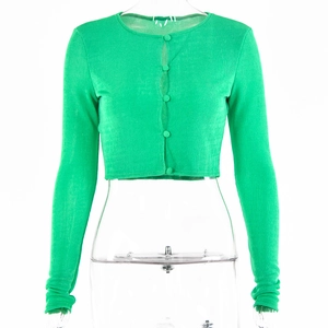 Détail d'un cardigan vert en maille côtelée avec fermeture boutonnée et coupe courte