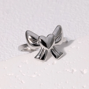 Silver bow ring with heart center in stainless steel, minimalist style on white background