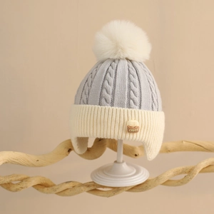Detail of baby cable knit hat featuring a contrast fluffy pompom and CHOCO logo