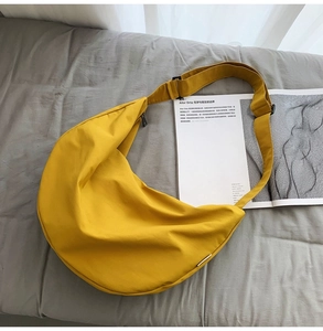 Detail of a mustard yellow crescent moon crossbody bag made of lightweight nylon fabric