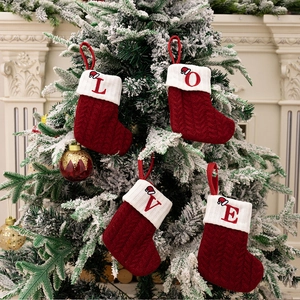 Close-up of red knit Christmas stockings with LOVE embroidery hanging on a tree