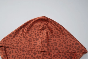 Détail du tissu à imprimé léopard et des coutures du sweat à capuche en marron rouge