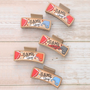 Brown PU leather game day hair clips with football helmet and star prints on wood