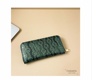 Detail view of deep green embossed leather wallet with golden zipper on beige background