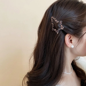 Dettaglio di un fermaglio per capelli a forma di stella leopardato indossato da modella