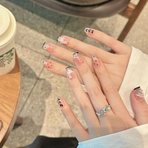 Detail of French style press-on nails with 3D butterflies, pearls, and black polka dots