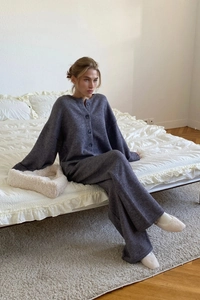 Detail of grey knit cardigan and wide-leg trousers set in a cozy home setting