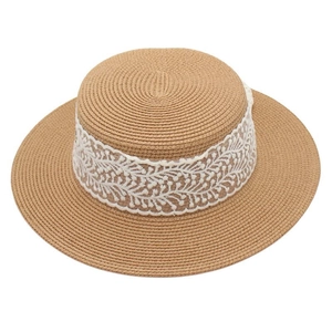 Vue de dessus d'un chapeau de paille plat avec dentelle blanche aux motifs floraux