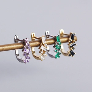 Macro shot of U-shaped silver earrings with zircon stones in purple, green, and black