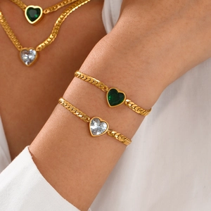 Gold heart jewelry set with green crystals including a necklace and bracelet on model