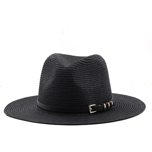 Detail of black straw fedora with decorative leather band and golden buckle finish