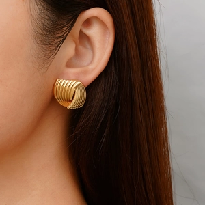 Macro detail of gold ribbed stud earrings featuring a vintage shell-like textured design