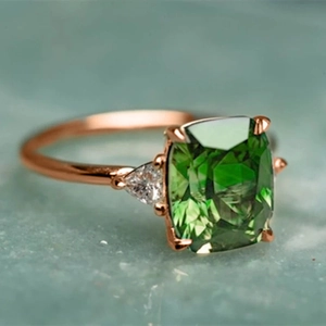 Elegant rose gold ring featuring a green cushion-cut zircon and triangular side stones